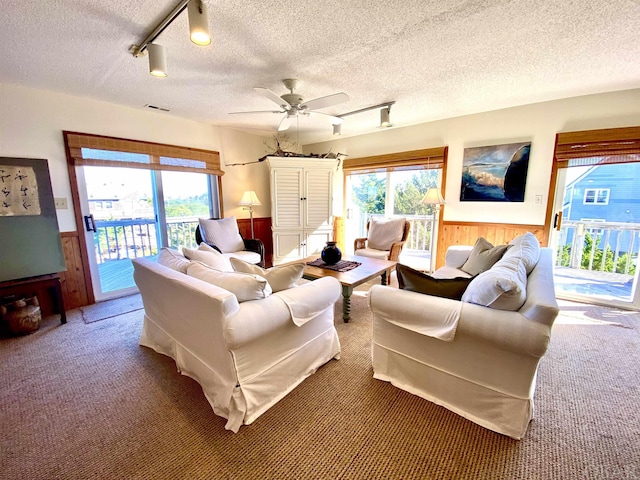 living area with a healthy amount of sunlight, a wainscoted wall, carpet, and visible vents