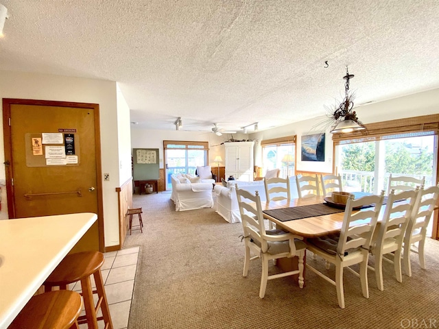 dining room featuring light carpet, ceiling fan, and a textured ceiling