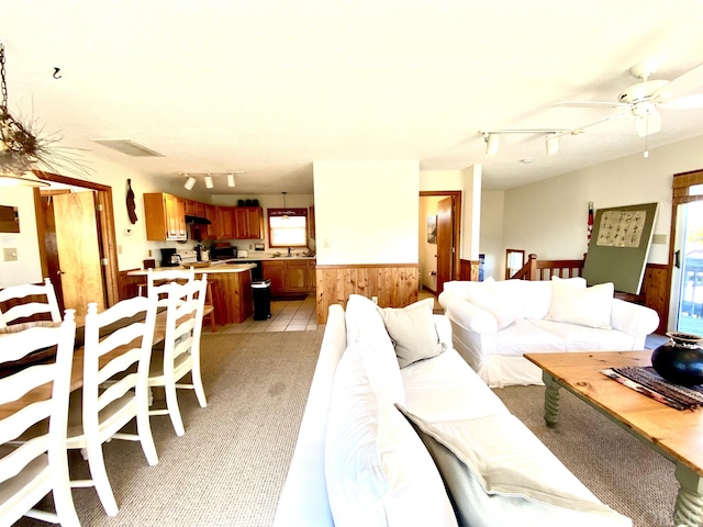 living area with light carpet, visible vents, a ceiling fan, wainscoting, and track lighting