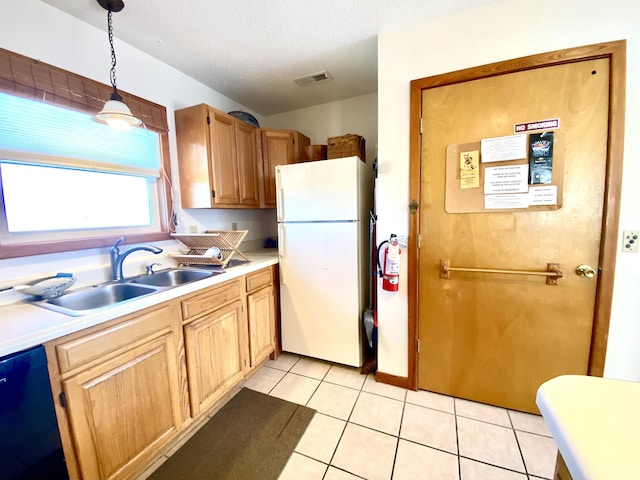 kitchen featuring a sink, visible vents, hanging light fixtures, light countertops, and freestanding refrigerator