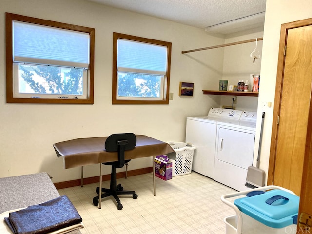 clothes washing area with light floors, washing machine and dryer, a textured ceiling, laundry area, and baseboards