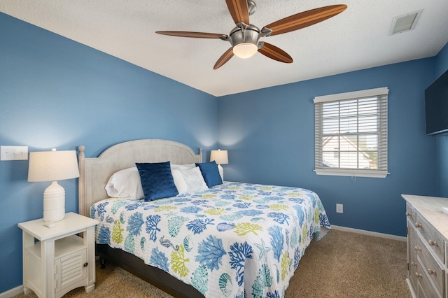 carpeted bedroom with a textured ceiling, ceiling fan, baseboards, and visible vents