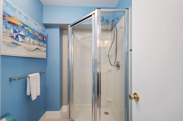 bathroom featuring baseboards and a shower stall