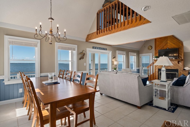 dining space with lofted ceiling, a textured ceiling, a water view, and light tile patterned flooring