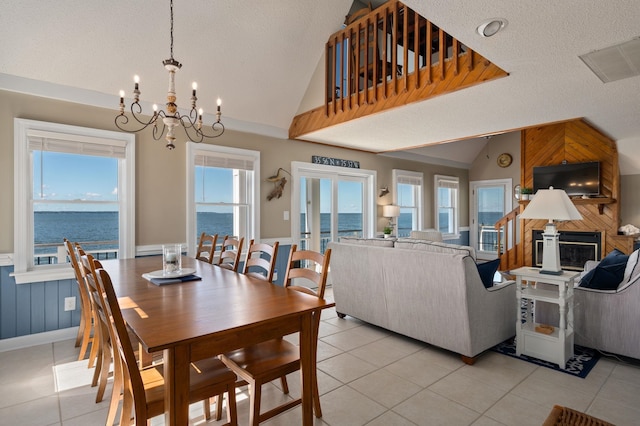 dining area featuring an inviting chandelier, a textured ceiling, a fireplace, light tile patterned flooring, and lofted ceiling