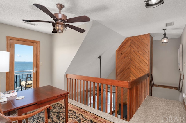 home office featuring a water view, ceiling fan, visible vents, and a textured ceiling