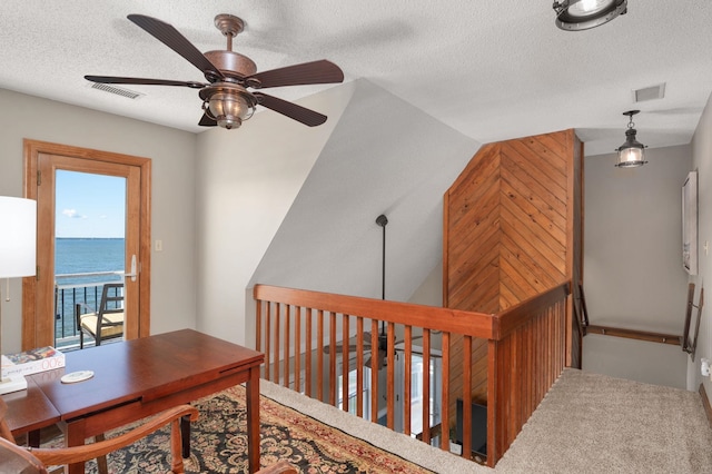 office space with a water view, visible vents, a ceiling fan, and a textured ceiling