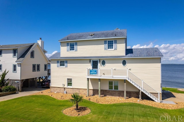 back of house with a carport, a water view, a lawn, and stairway