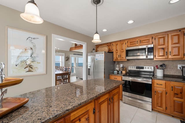 kitchen featuring stainless steel appliances, brown cabinetry, backsplash, and light tile patterned flooring
