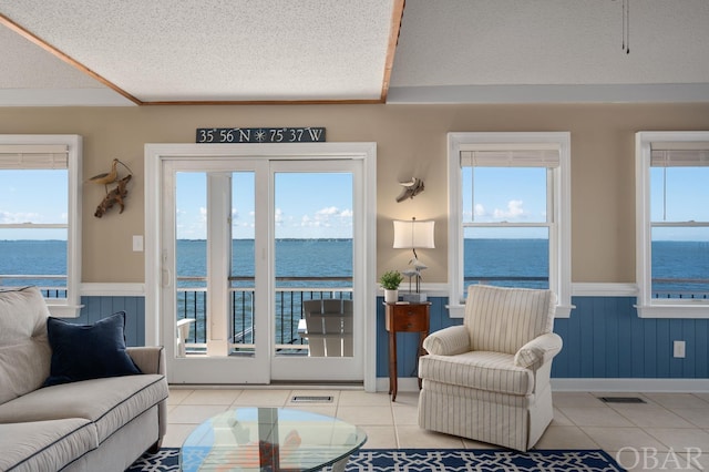 living room featuring a wainscoted wall, a water view, and plenty of natural light