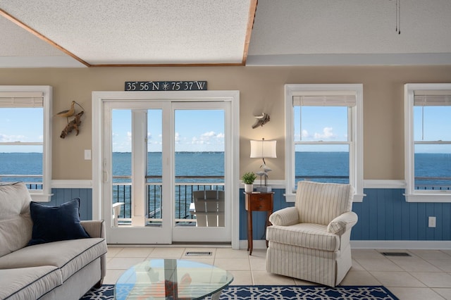 interior space featuring a textured ceiling, a wainscoted wall, and a healthy amount of sunlight
