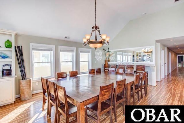 dining room with baseboards, visible vents, an inviting chandelier, light wood-type flooring, and high vaulted ceiling