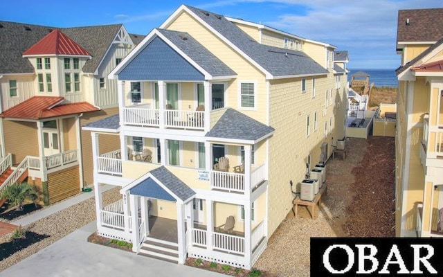 view of front of house with roof with shingles and a balcony