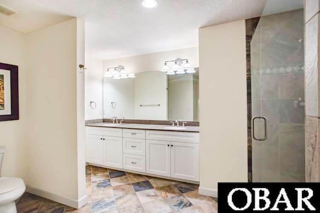 full bath featuring double vanity, baseboards, toilet, a shower stall, and a sink