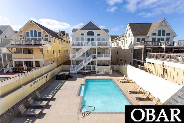 rear view of property with stairway, a patio area, fence, and a community pool