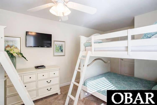 bedroom with light colored carpet, built in study area, and ceiling fan