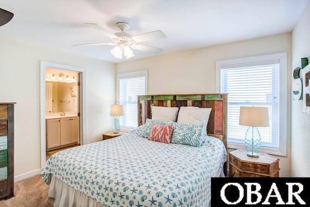 carpeted bedroom featuring ensuite bath, baseboards, and a ceiling fan