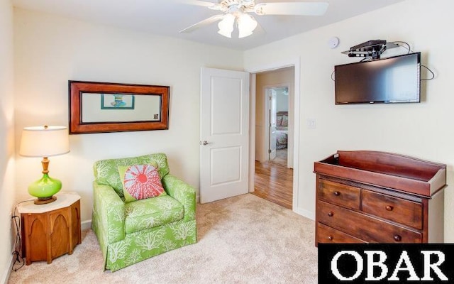 living area with ceiling fan and carpet