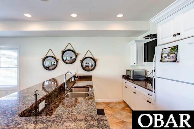 kitchen with freestanding refrigerator, stainless steel microwave, a sink, and white cabinetry