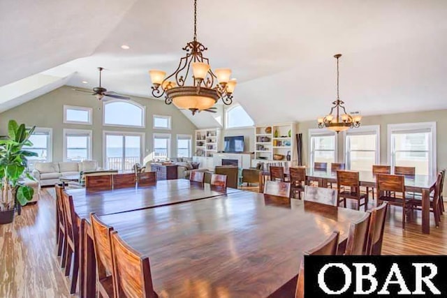 dining room featuring lofted ceiling, a fireplace, wood finished floors, and ceiling fan with notable chandelier