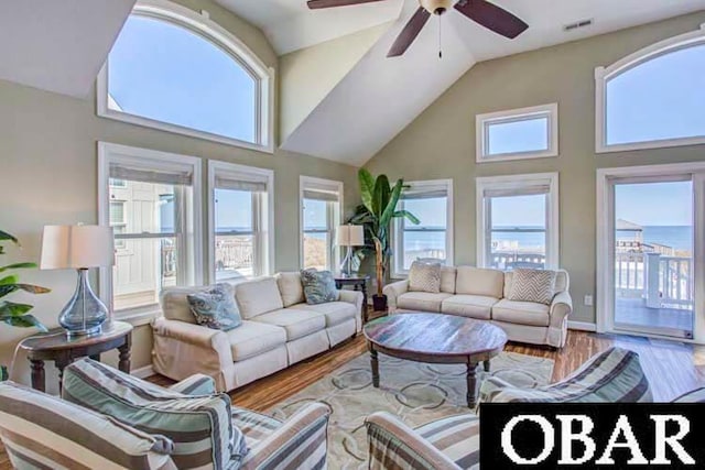 living area with ceiling fan, high vaulted ceiling, wood finished floors, and baseboards