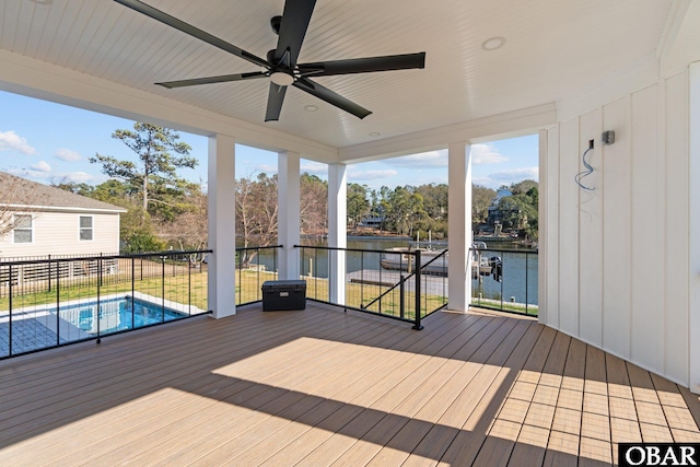 wooden deck with a ceiling fan, a fenced in pool, and a water view