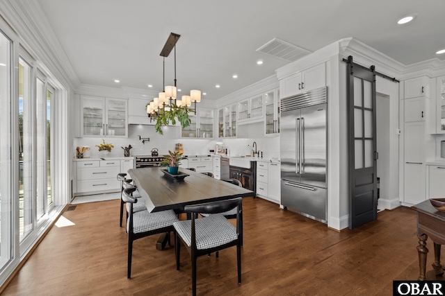 dining area with ornamental molding, a barn door, plenty of natural light, and visible vents