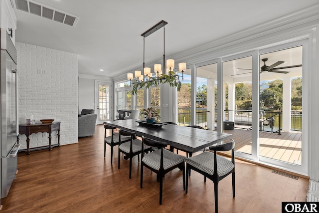 dining space featuring ceiling fan with notable chandelier, visible vents, crown molding, and wood finished floors