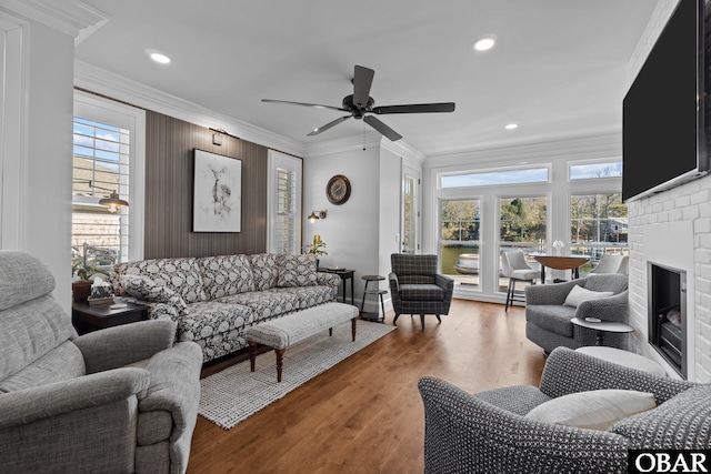 living area featuring light wood finished floors, plenty of natural light, a fireplace, and ornamental molding