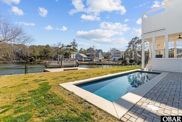 outdoor pool with a residential view, a water view, a yard, and a boat dock