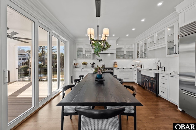 dining area featuring ornamental molding, recessed lighting, dark wood-type flooring, and ceiling fan with notable chandelier