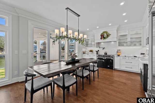 dining room with recessed lighting, crown molding, dark wood-type flooring, baseboards, and an inviting chandelier