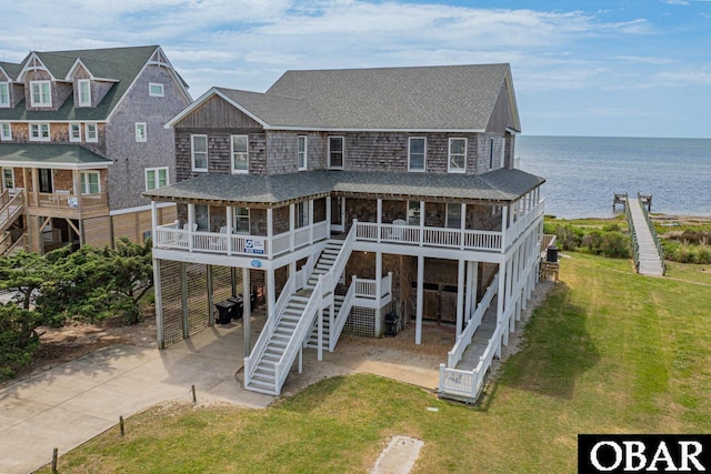 view of front of property with concrete driveway, a carport, stairway, and a water view