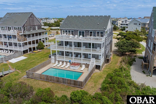 rear view of house featuring a residential view, a community pool, a shingled roof, a yard, and a fenced backyard