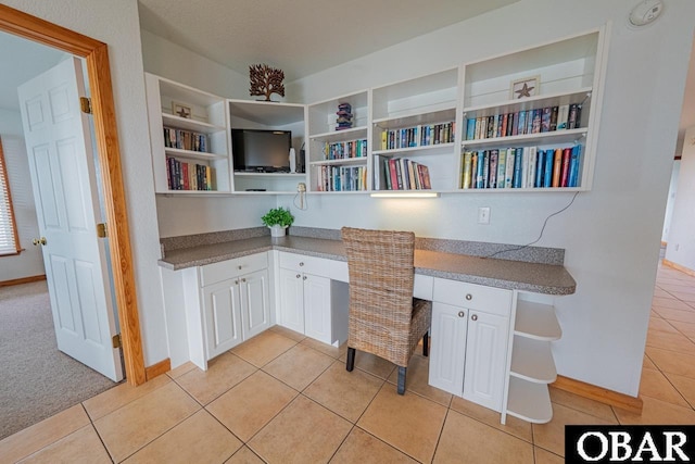office featuring light tile patterned floors, baseboards, and built in study area