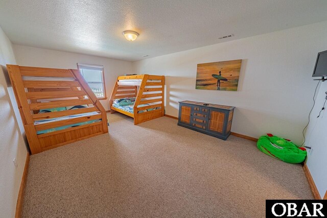 carpeted bedroom featuring a textured ceiling, visible vents, and baseboards