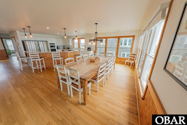 dining area with light wood finished floors, recessed lighting, and a chandelier