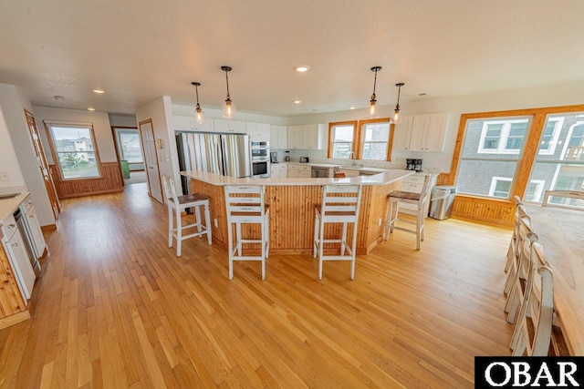 kitchen featuring a wealth of natural light, stainless steel appliances, light wood-type flooring, and white cabinets