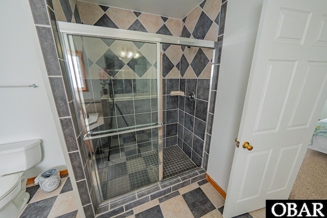 bathroom featuring baseboards, a stall shower, and toilet