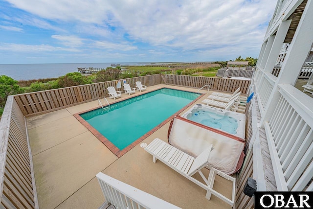 view of swimming pool with a water view, an in ground hot tub, and a fenced in pool