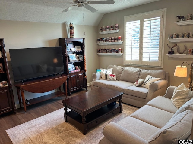 living area with ceiling fan, a textured ceiling, vaulted ceiling, and wood finished floors