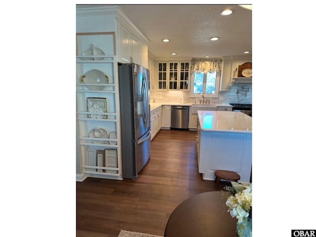 kitchen with dark wood finished floors, light countertops, appliances with stainless steel finishes, glass insert cabinets, and white cabinetry