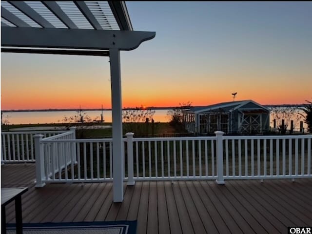 deck at dusk featuring a water view