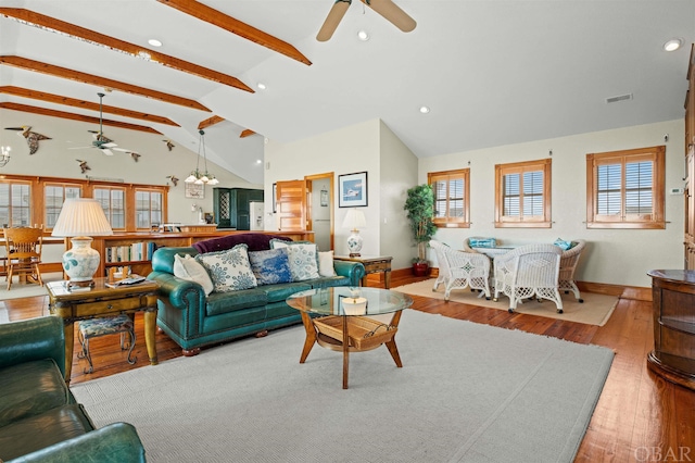 living area with visible vents, baseboards, lofted ceiling with beams, light wood-type flooring, and ceiling fan with notable chandelier