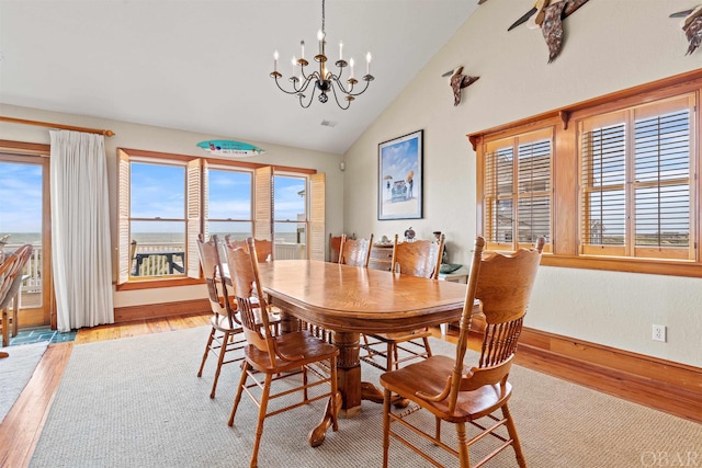 dining space featuring vaulted ceiling, baseboards, light wood-style flooring, and a notable chandelier