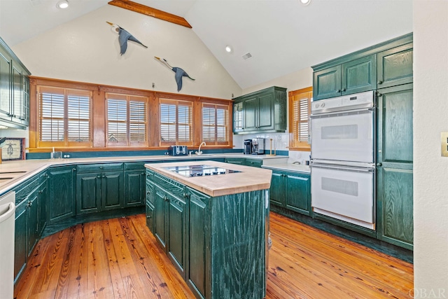 kitchen with a center island, white appliances, green cabinetry, and vaulted ceiling