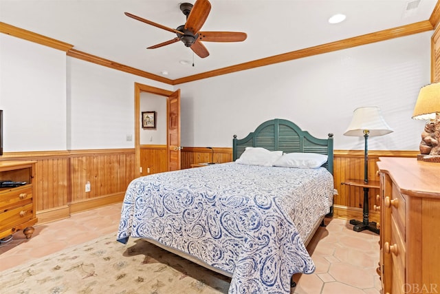 bedroom with ceiling fan, crown molding, and wainscoting