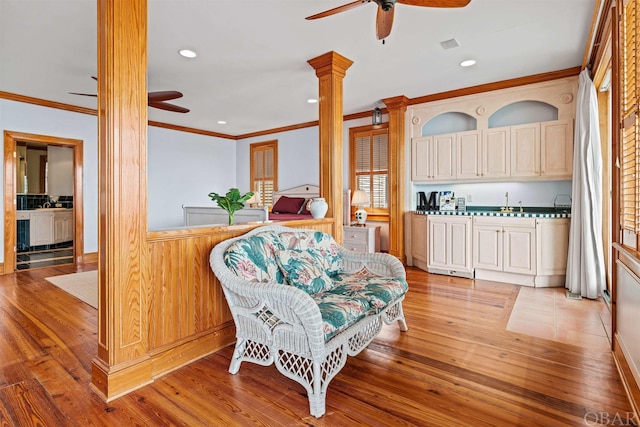 interior space with crown molding, decorative columns, visible vents, ceiling fan, and light wood-type flooring