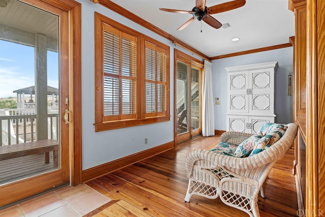 sitting room with light wood finished floors, baseboards, visible vents, a ceiling fan, and crown molding