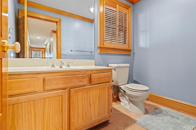 bathroom with toilet, vanity, ornamental molding, and tile patterned floors